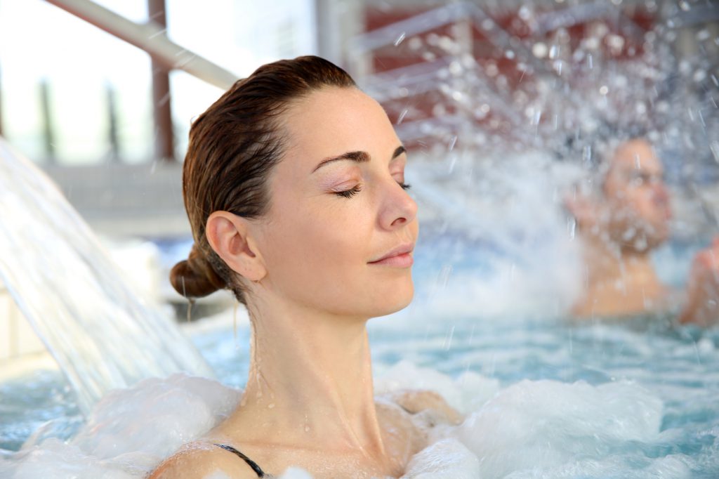 Woman enjoying hydrojet shower in spa pool